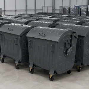 Contenedores de residuos de metal gris oscuro con cuatro ruedas, dispuestos en una fábrica para la producción en serie