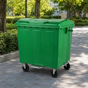 1100L green metal waste container with foot pedal and four caster wheels on an outdoor park walkway