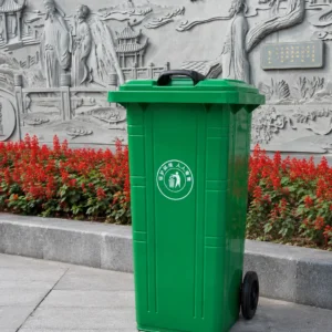 Green two-wheel plastic waste bin installed beside a traditional cultural relief wall Green two-wheel plastic waste bin installed beside a traditional cultural relief wall