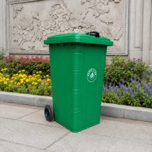 Green Plastic Wheelie Bin for Landscaped Public Areas | KOVANTO Green two-wheel plastic wheelie bin beside a landscaped cultural relief wall