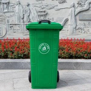 Green Plastic Wheelie Bin in Public Cultural Area | KOVANTO Green two-wheel plastic wheelie bin in a landscaped public cultural area